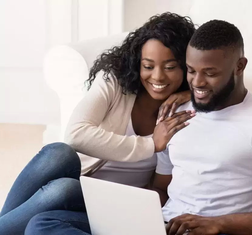 A smiling couple looking at a computer screen together.