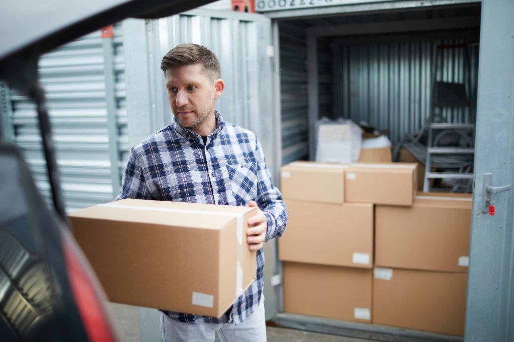 A man loading boxes from his car into a self-storage unit.
