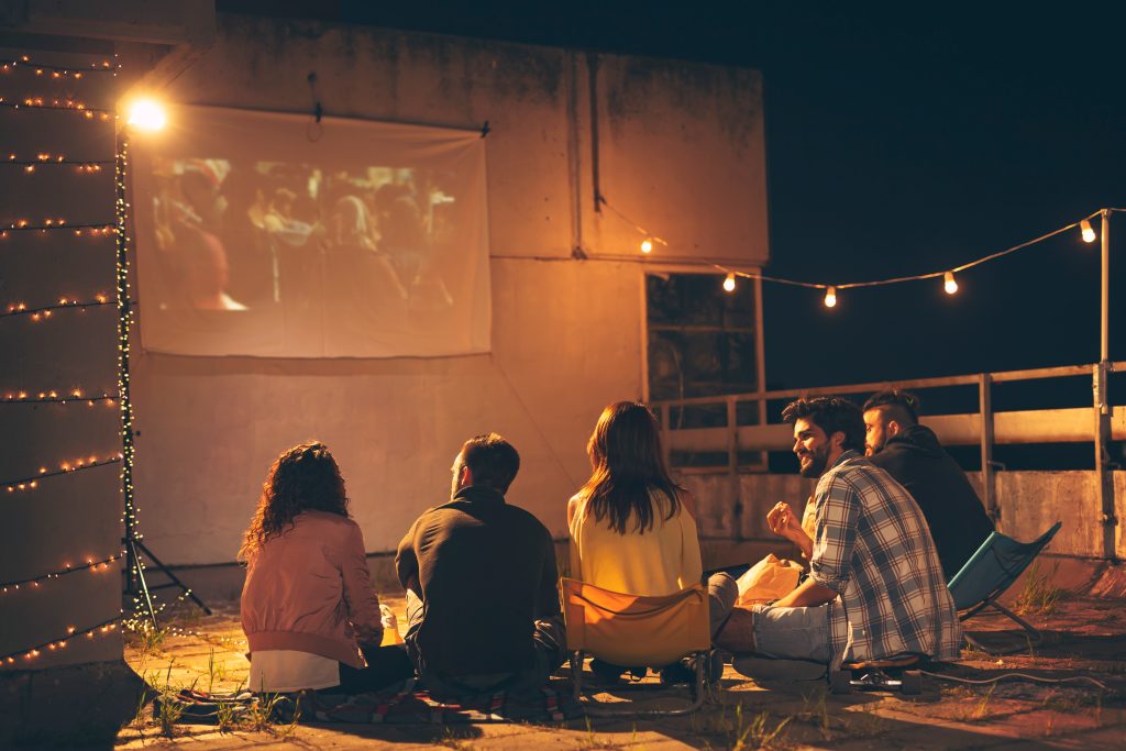 A group of friends having an outdoor movie night.