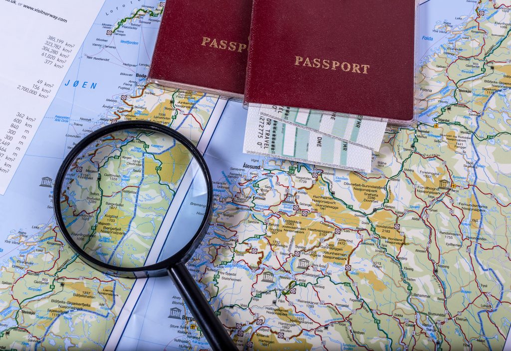 A map with two passports and a magnifying glass on top of it.