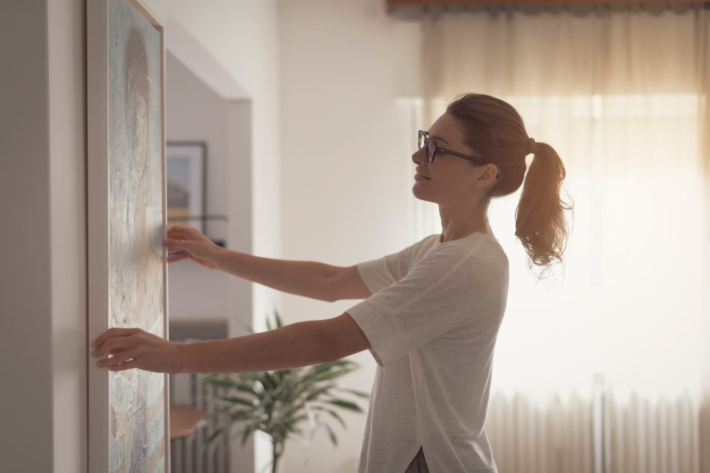 Woman hanging art on a wall.