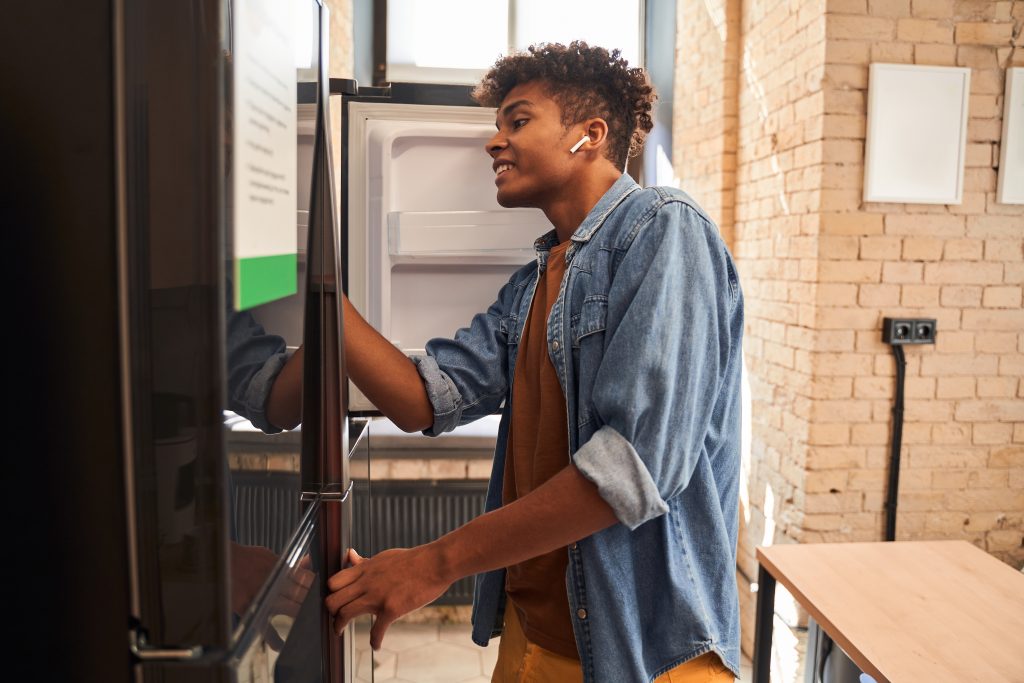 A young man cleaning out his fridge.