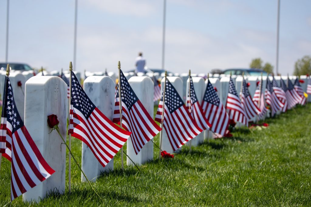 A row of gravestones with flags in front of them on Memorial Day.