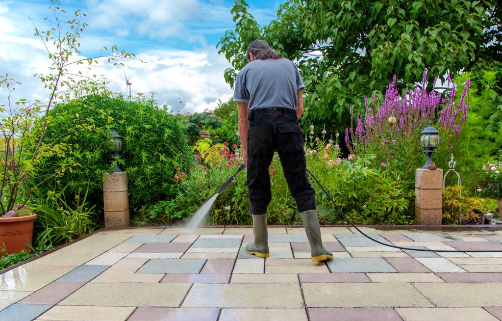 Man cleaning a stone patio with a pressure washer.