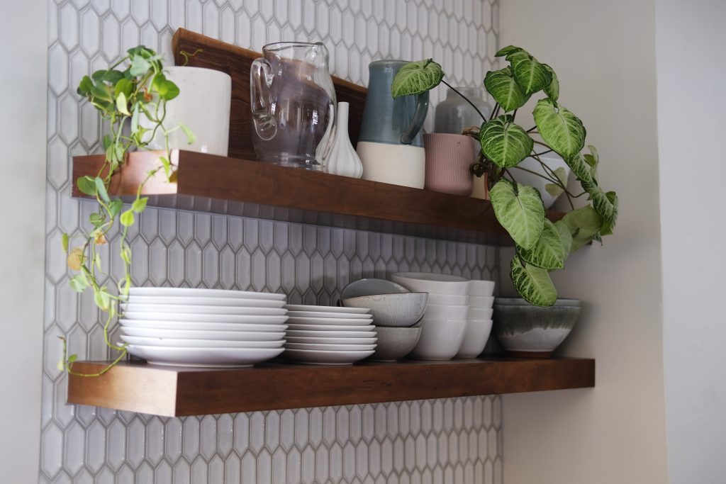 Floating shelves in a kitchen holding plants and dishes.