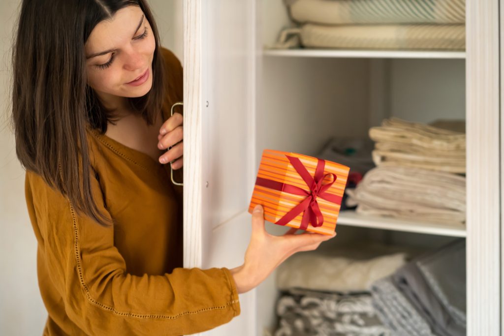 Woman hiding a gift in a linen closet.