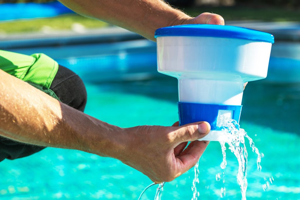 Hands holding a pool filter near a pool.