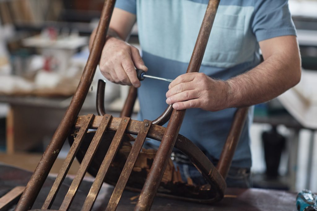 Man fixing a vintage wood chair.
