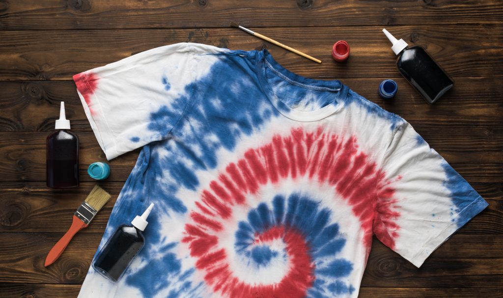 A red, white, and blue tie-dyed shirt with supplies around it.