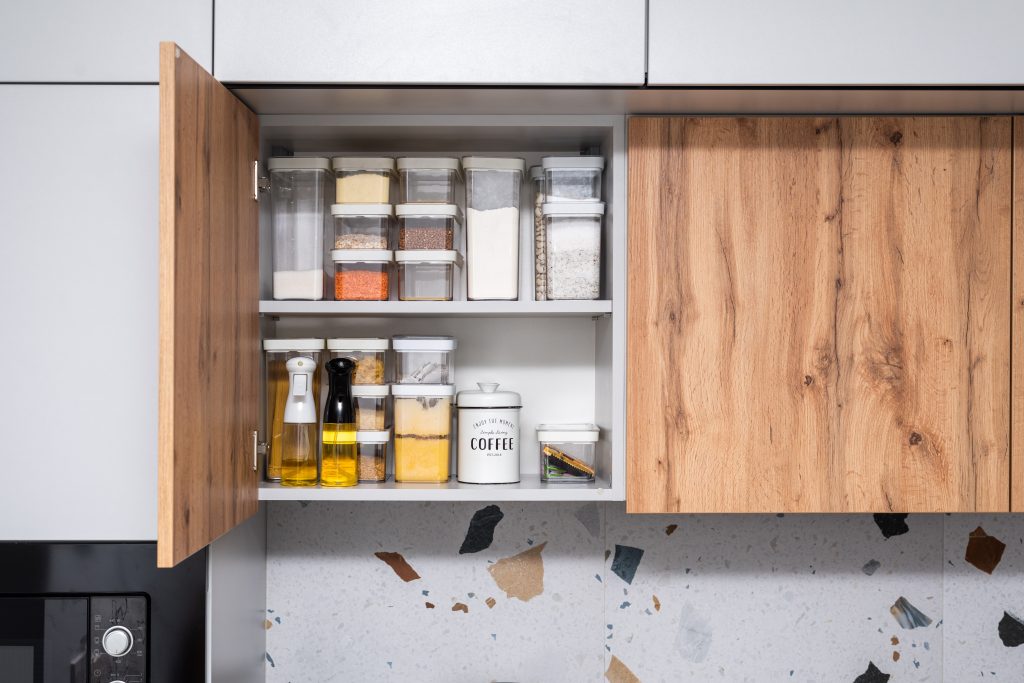 An open kitchen cabinet with organized ingredients.