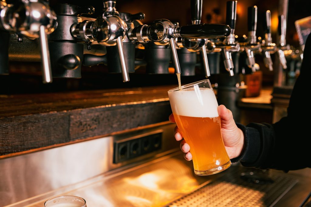 A bartender filling a glass with beer from a tap.