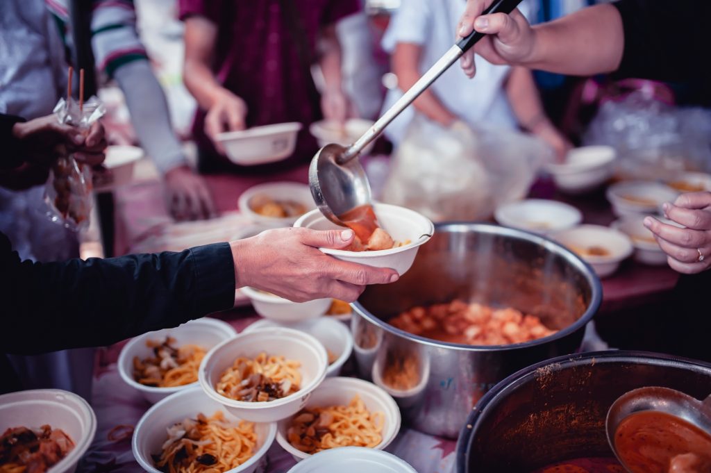 Volunteers hand out bowls of soup at a soup kitchen.