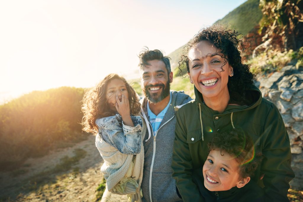 A family smiling surrounded by grassy sand dunes.