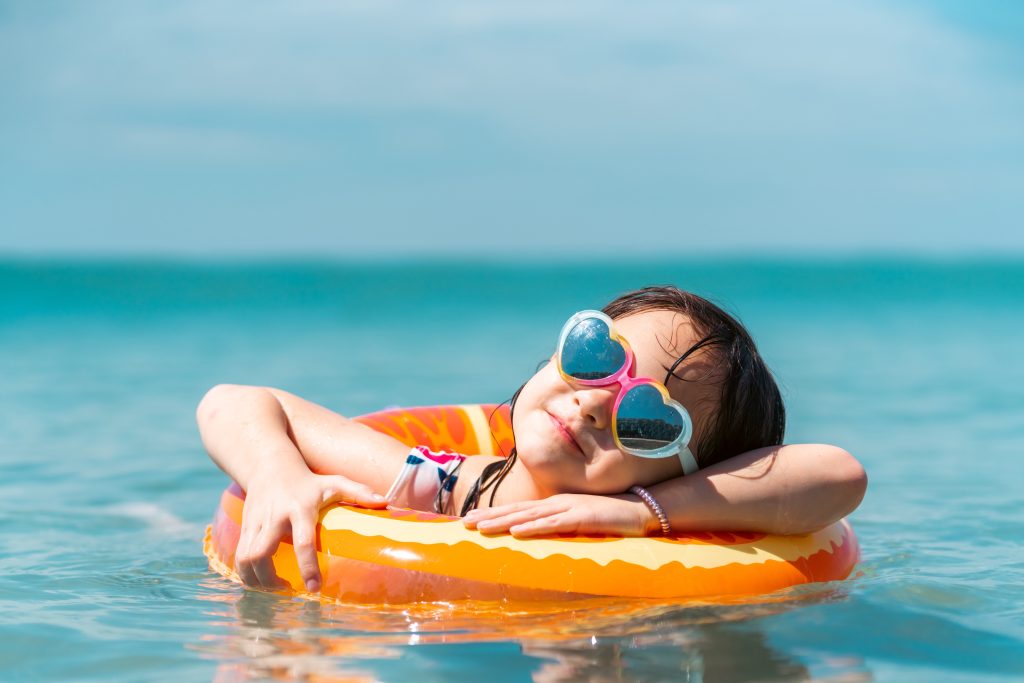 A little girl floating happily in an innertube on the ocean.