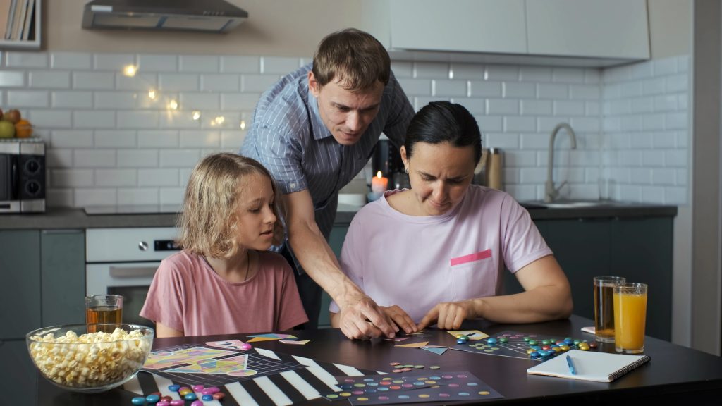 Parents and a daughter playing board games at a kitchen table.