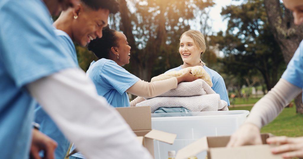 Woman handing clothes to volunteers at a donation center.
