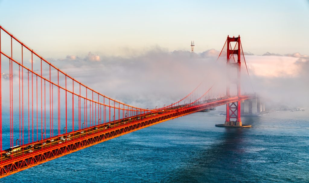The Golden Gate Bridge shrouded in fog at sunrise.