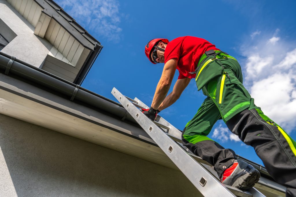 A roof inspector climbing a ladder to a roof.