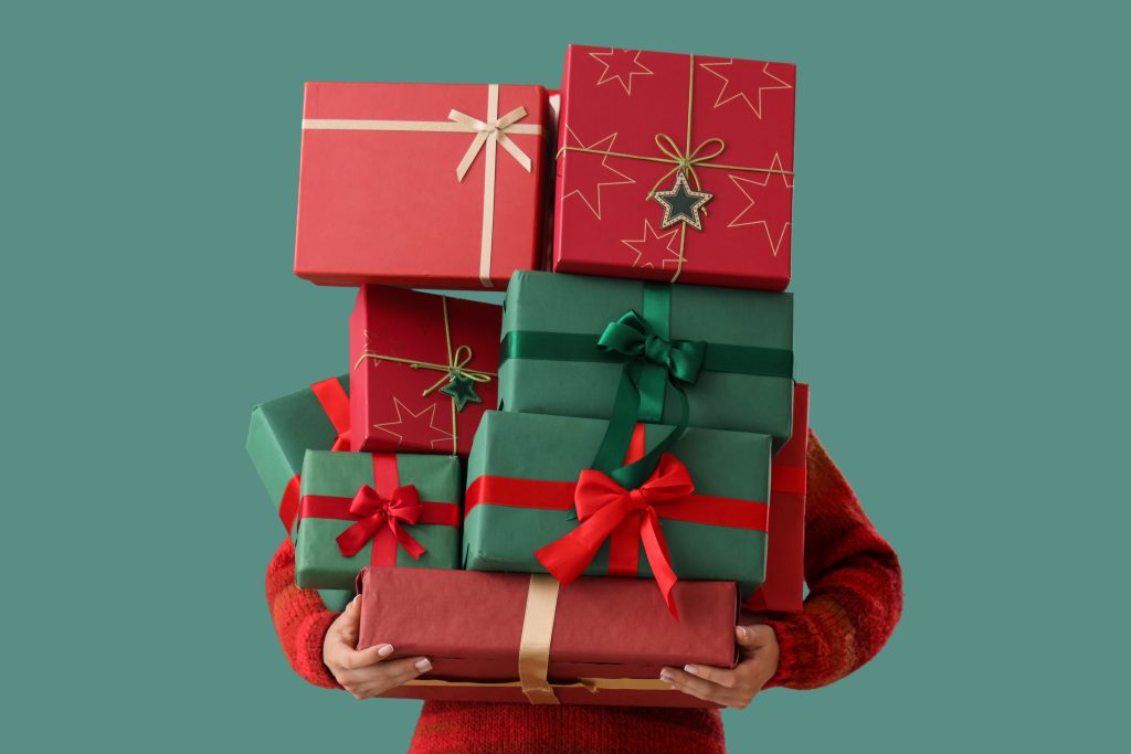 Person holding a stack of christmas presents.