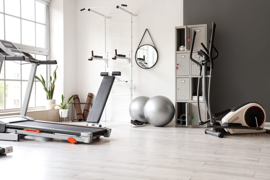 A home gym in a spare bedroom, with a treadmill, yoga balls, and other workout equipment.