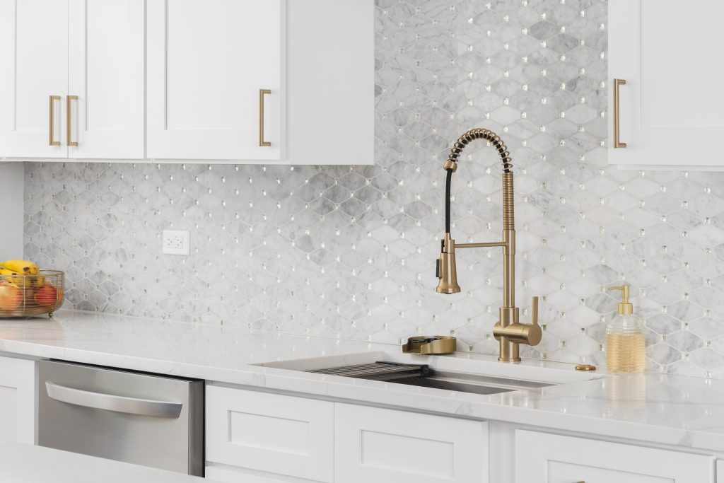 A white kitchen with gray backsplash.