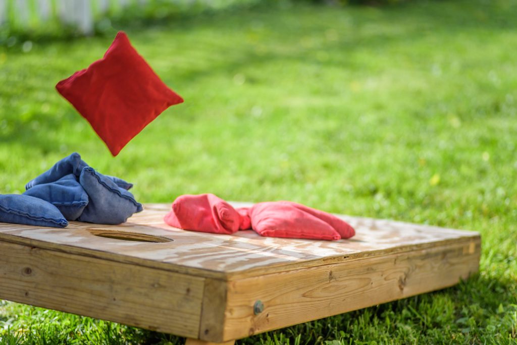 A cornhole board with red and blue bags on it.