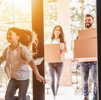 A happy family moving cardboard boxes into their new home.